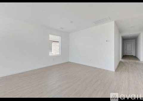 A spacious room with wooden flooring and white walls.