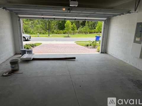 A garage with a view of a driveway and trees.