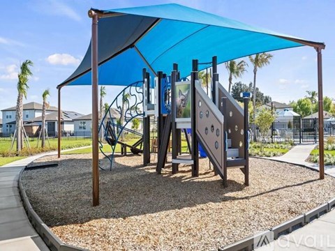 A playground with a blue canopy and a slide.