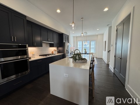 A modern kitchen with dark cabinets and stainless steel appliances.