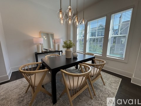 A dining room with a black table and wooden chairs.