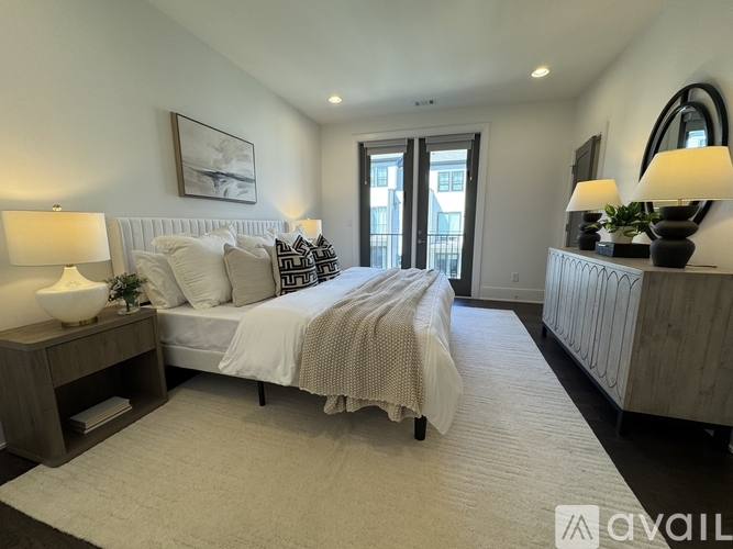 A bedroom with a large bed, a nightstand with a lamp, and a painting on the wall.
