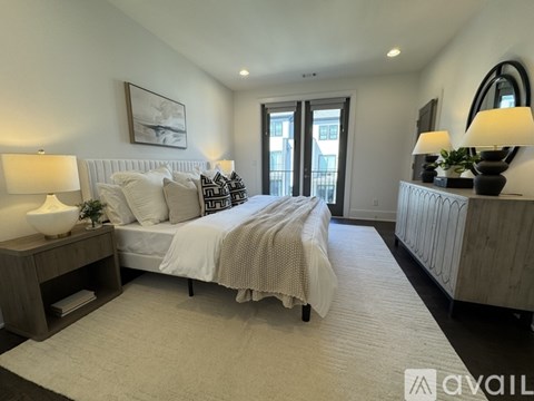 A bedroom with a large bed, a nightstand with a lamp, and a painting on the wall.