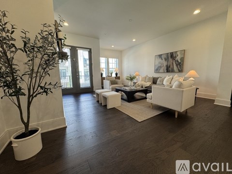A living room with a tree, couch, and a painting on the wall.
