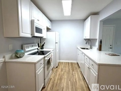 A kitchen with white cabinets and a wooden floor.