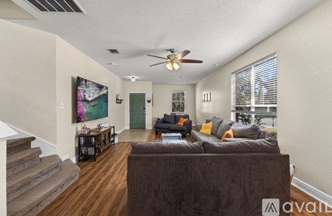 A living room with a brown couch and a painting on the wall.