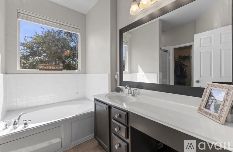 A bathroom with a large mirror and a window that shows trees outside.