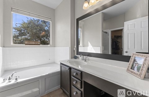 A bathroom with a large mirror and a window that shows trees outside.