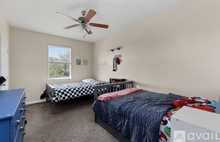 A bedroom with two beds and a ceiling fan.
