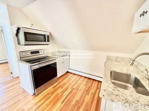 A kitchen with a sink, stove, and microwave.