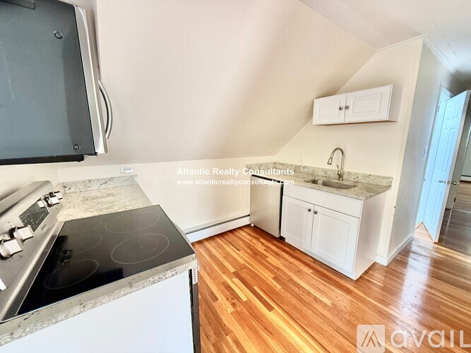 A kitchen with a stove top oven and wooden floors.