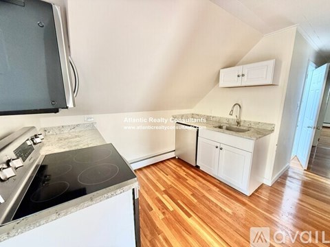 A kitchen with a stove top oven and wooden floors.