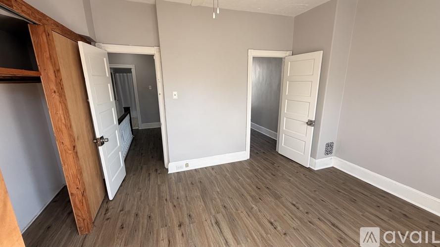 A room with wooden floors and two white doors.