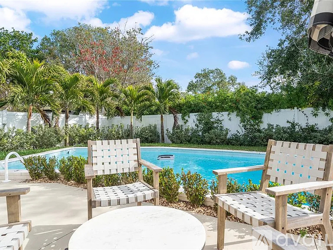 Two chairs and a table are placed in front of a pool.
