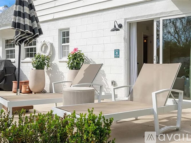 A white building with a patio and a striped umbrella.