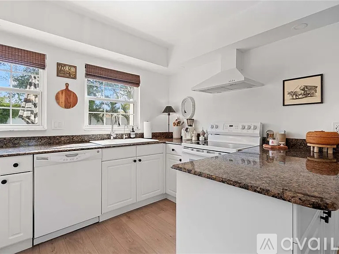 A kitchen with white cabinets and a granite countertop.