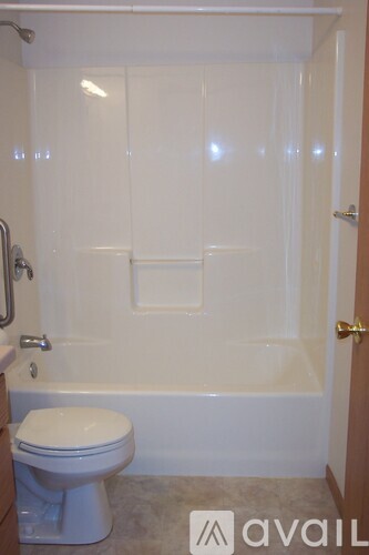 A white toilet is in a bathroom with a tub and shower.