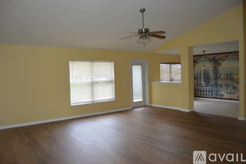 A room with a ceiling fan and two windows.