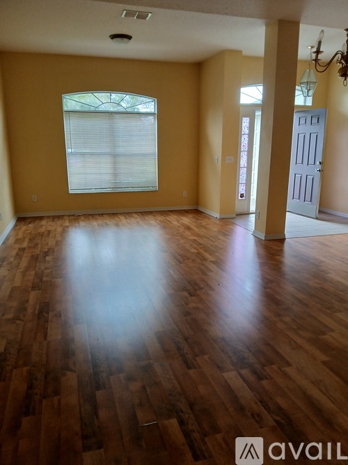 A room with wooden floors and a window with blinds.