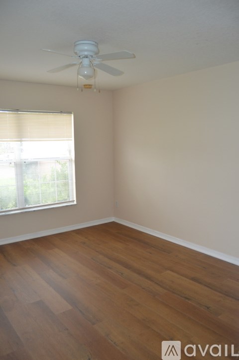 A room with a ceiling fan and wooden flooring.