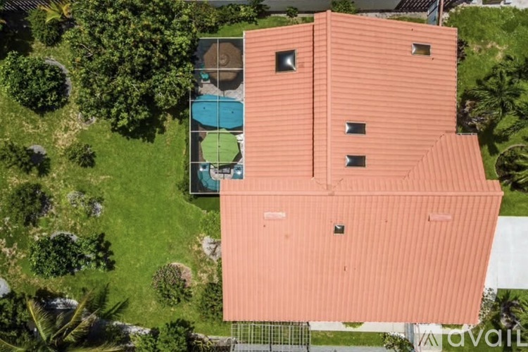 A house with a red roof and a pool in the backyard.