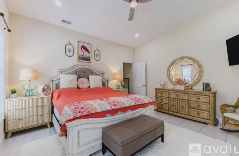 A bedroom with a large bed, a dresser, and a mirror.