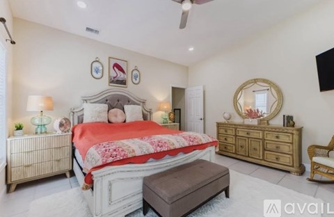 A bedroom with a large bed, a dresser, and a mirror.