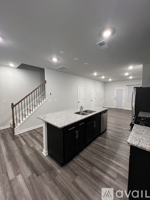 A kitchen with a granite countertop and a staircase in the background.