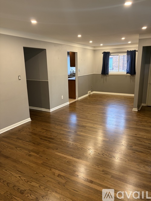 A room with wooden flooring and a window with curtains.