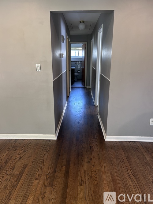 A hallway with wood flooring and white walls.
