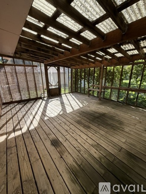 A wooden deck with a glass roof and a view of trees outside.