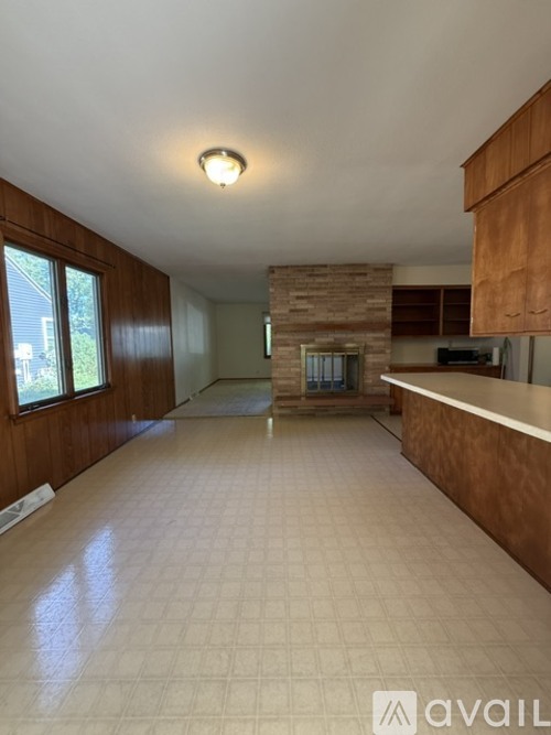 A spacious kitchen with a tiled floor and wooden cabinets.