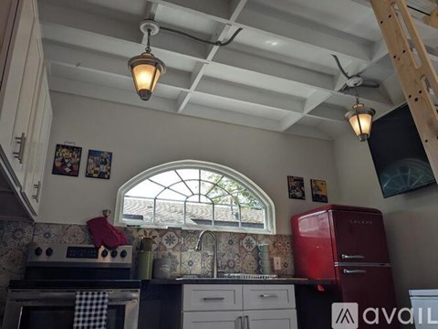 A kitchen with a red fridge and a window with a view of a tree.
