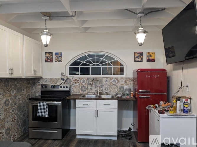 A kitchen with a red fridge and a black stove.