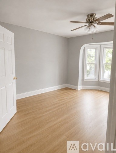 A room with a ceiling fan and wooden flooring.
