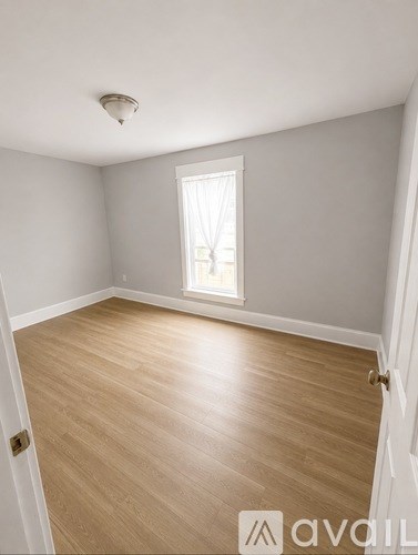 A room with wooden flooring and a window letting in light.