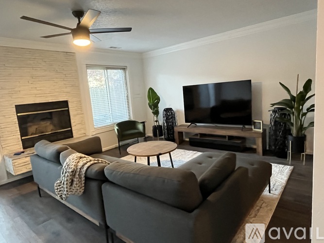 A living room with a grey couch, a fireplace, and a television.