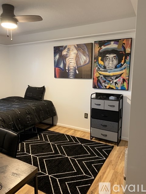 A bedroom with a bed, a chair, a rug and two paintings on the wall.