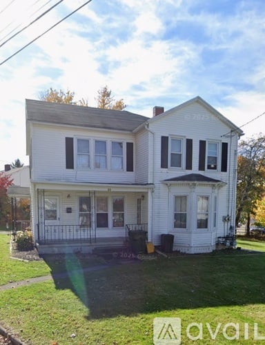 A two-story white house with black shutters and a black front door.