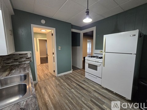 A kitchen with a white refrigerator, wooden floors, and a marble countertop.