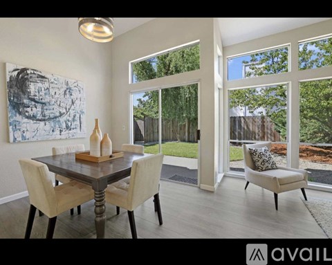 A dining room with a table set for two and a view of a backyard.