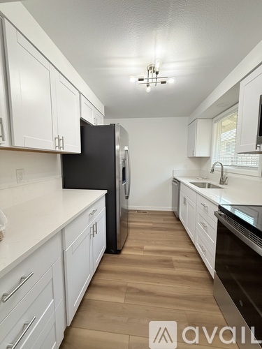 A kitchen with white cabinets and a black fridge.