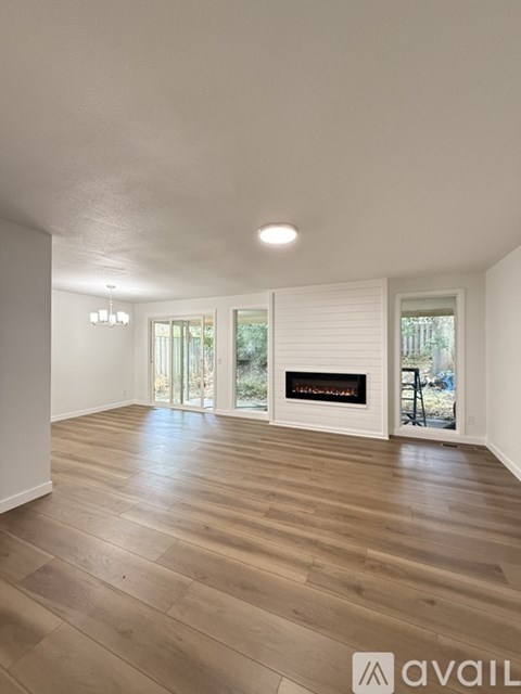 A spacious room with a fireplace and wooden flooring.