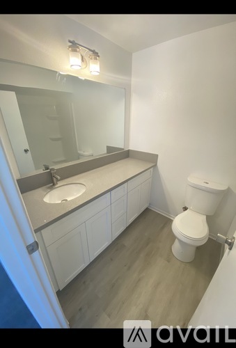 A bathroom with a toilet, sink, and mirror.