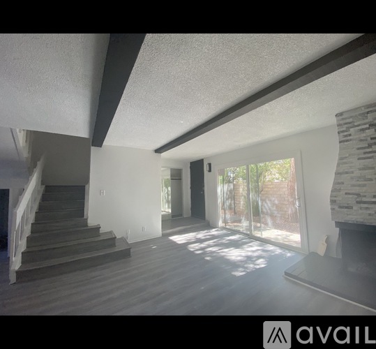 A spacious room with wooden floors and a staircase leading to another level.