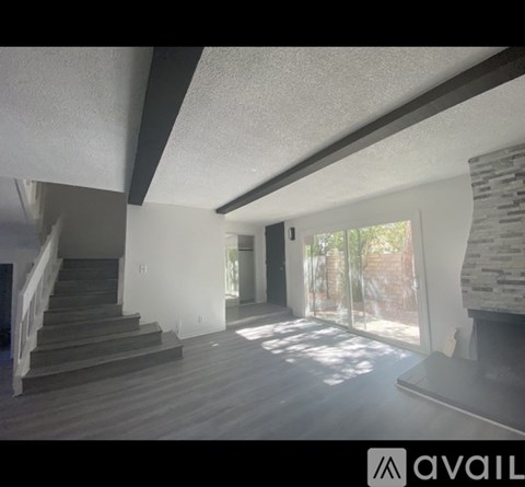 A spacious room with wooden floors and a staircase leading to another level.