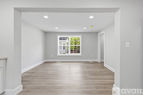 A spacious room with wooden flooring and a large window.