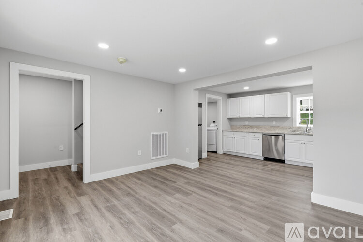 A spacious kitchen and living room with wood flooring and white walls.
