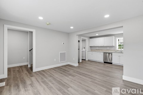 A spacious kitchen and living room with wood flooring and white walls.