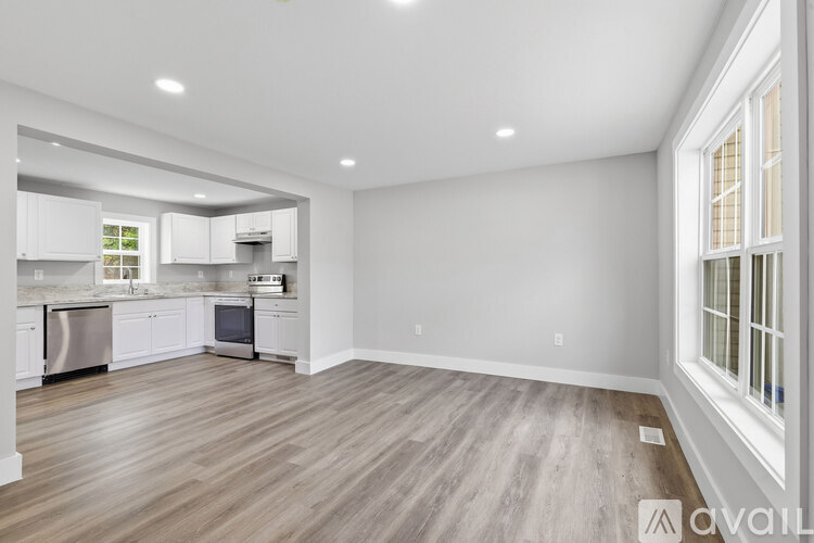 A spacious kitchen with white cabinets and a wooden floor.